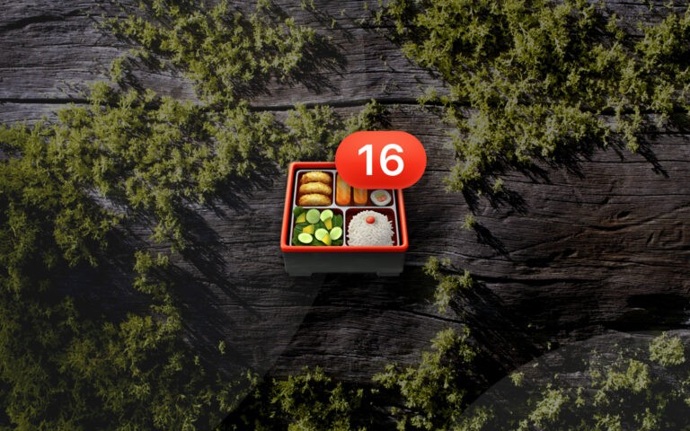 Bento box emoji with number 16 badge resting on a mossy wood background